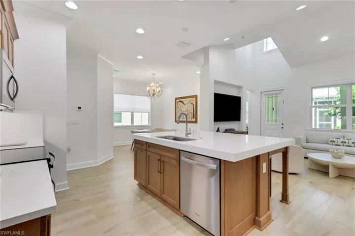 Kitchen with open floor plan, brown cabinetry, appliances with stainless steel finishes, recessed lighting, and a high ceiling