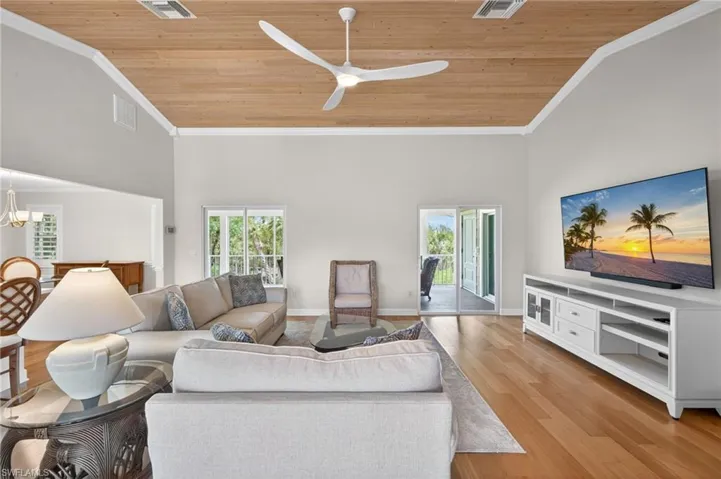 Spacious living area featuring a vaulted wood-finish ceiling, light wood-finish flooring, and white trim