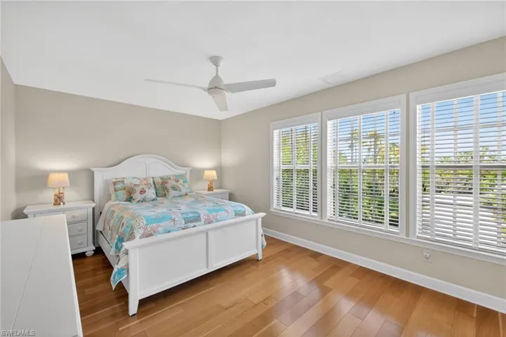Room featuring a white ceiling fan, light neutral wall paint, and wood-finish flooring