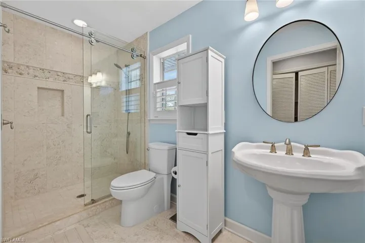 Glass-enclosed shower with stone tile surround and built-in niche