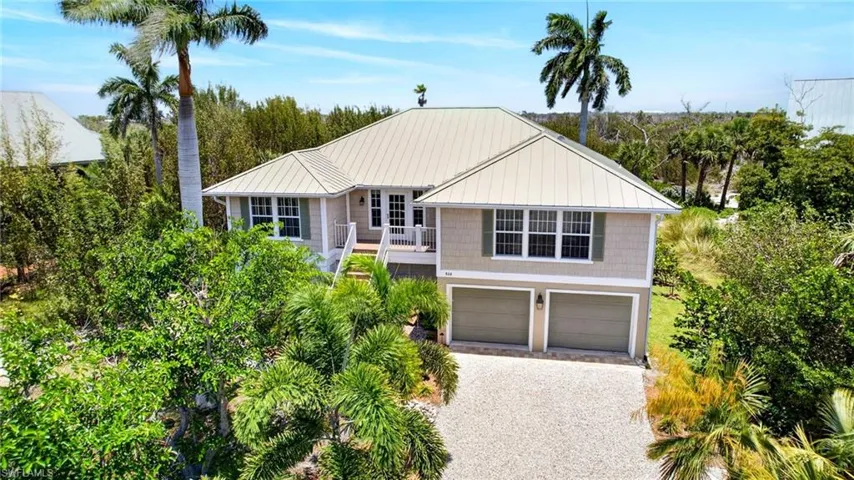 Coastal-style residence featuring a light-colored metal roof and a two-car garage