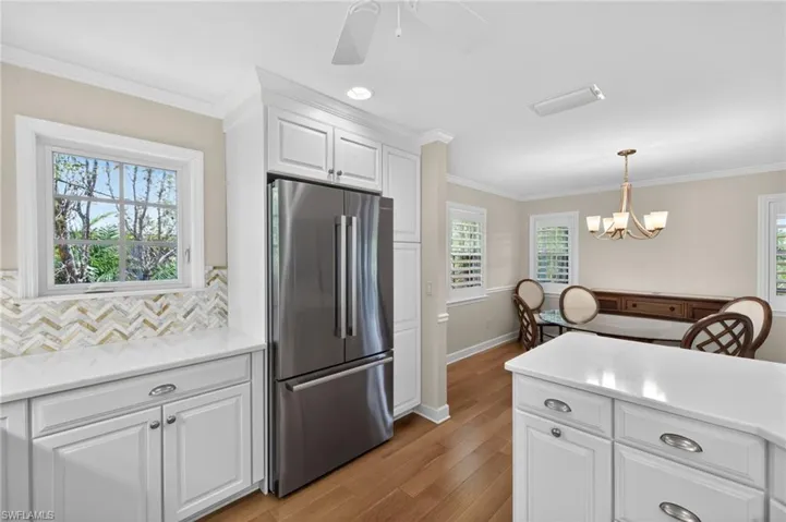 Kitchen featuring white shaker cabinetry, stainless steel refrigerator, white countertops, and a herringbone tile backsplash