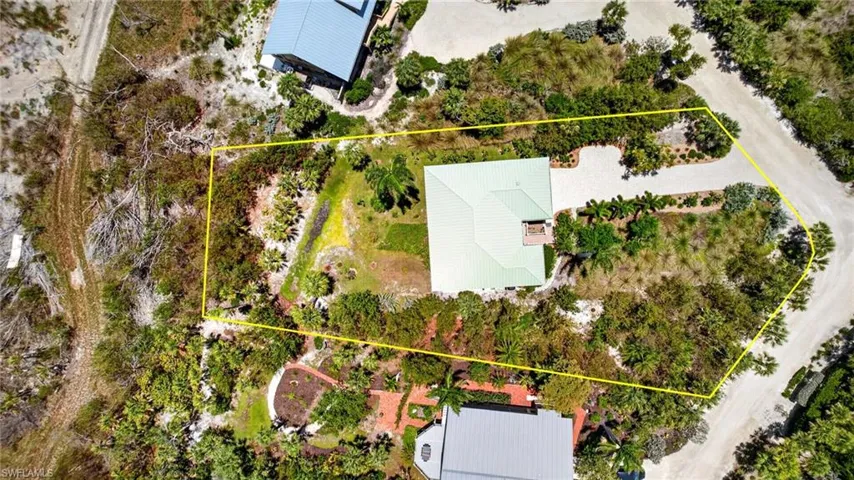 Aerial perspective showcasing a property with a light green roof, surrounded by mature trees and natural vegetation