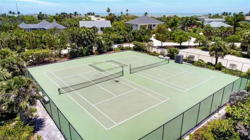 Two regulation-size Community tennis courts with light green playing surfaces and white court lines, enclosed by black chain-link fencing