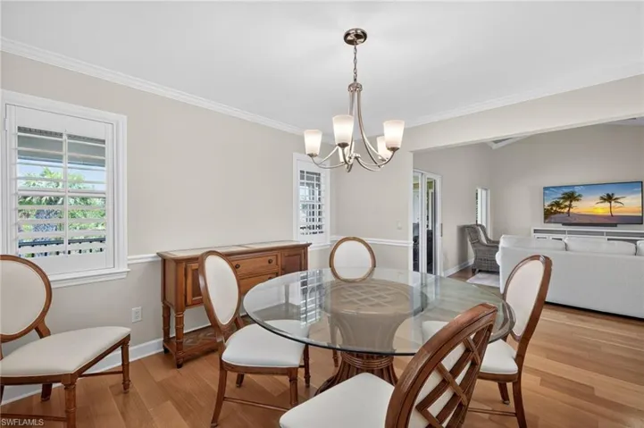 Dining area featuring wood-finish flooring, crown molding, and two windows with plantation shutters