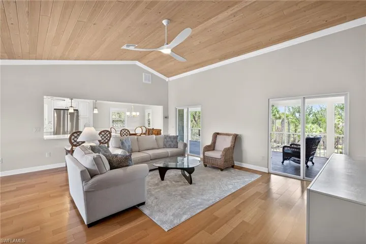 Vaulted wood-paneled ceiling with a ceiling fan, light wood-finish flooring, and multiple sliding glass doors opening to outdoor spaces