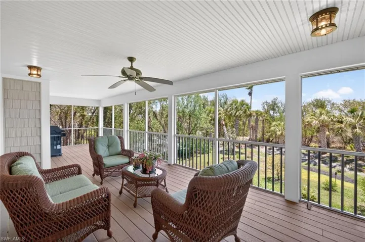 Screened outdoor living area with wood-finish flooring, a beadboard ceiling, and a ceiling fan