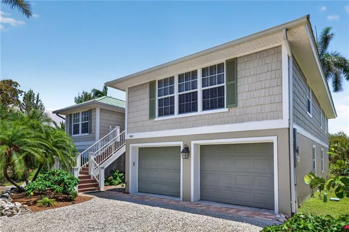 Two-story residence featuring a shingle and stucco exterior, dual garage doors, and a gravel driveway
