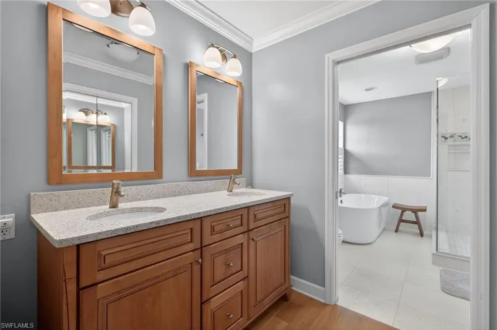 Dual wood-framed mirrors above a wood vanity with a speckled countertop