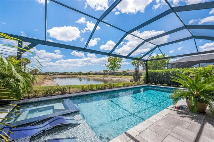 View of pool featuring a pool with connected hot tub, a lanai, and a water view