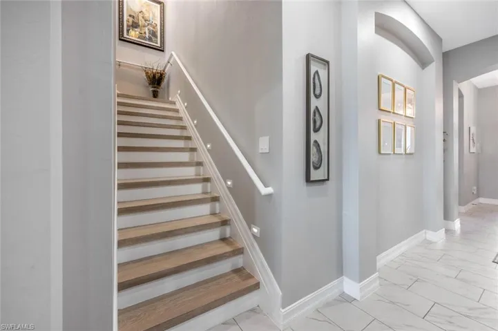 Stairway featuring marble finish floor, arched walkways, and baseboards