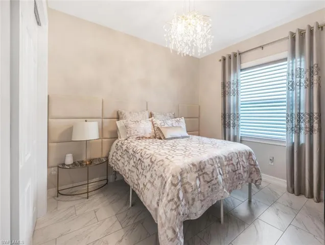 Bedroom with a chandelier, marble finish floor, and baseboards