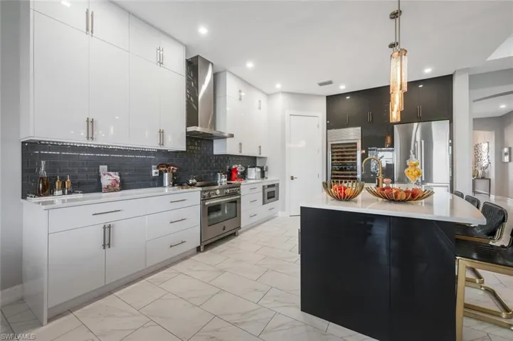 Kitchen with stainless steel appliances, wine cooler, wall chimney exhaust hood, marble finish floor, and light countertops