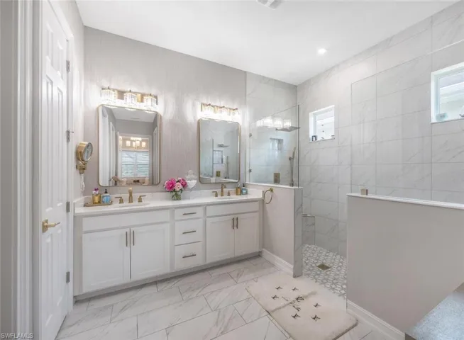 Full bathroom with a walk in shower, marble finish floor, double vanity, and a sink