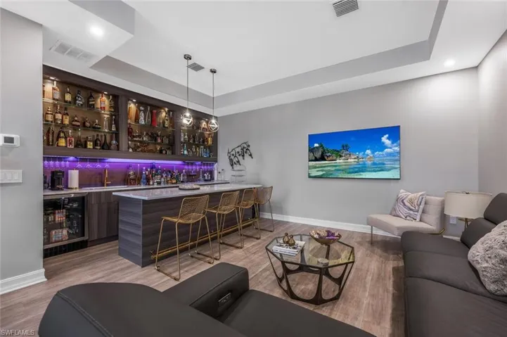 Bar with wine cooler, wet bar, a raised ceiling, and visible vents