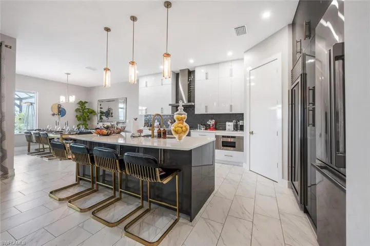 Kitchen with visible vents, wall chimney exhaust hood, light countertops, and marble finish floor