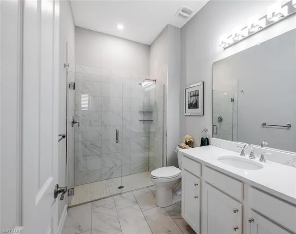 Bathroom featuring toilet, a stall shower, marble finish floor, and visible vents