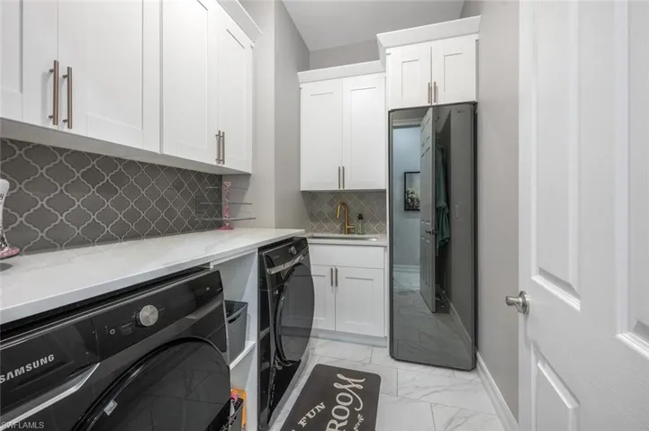 Washroom with washer and dryer, cabinet space, marble finish floor, a sink, and baseboards