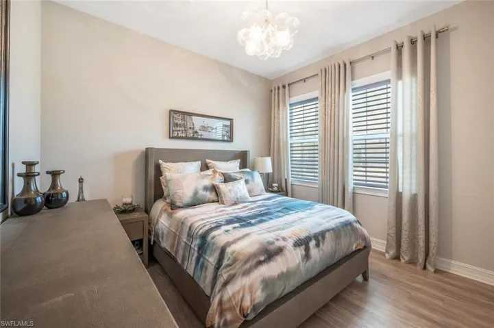 Bedroom with a chandelier, wood finished floors, and baseboards