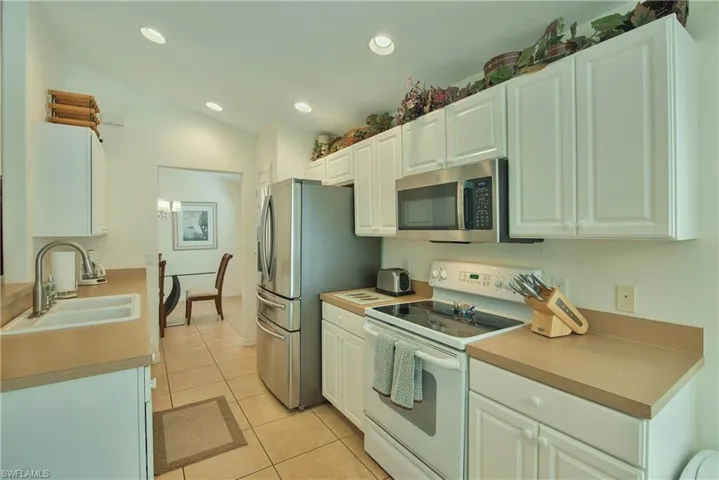 Kitchen featuring stainless steel appliances, white cabinetry, light tile patterned flooring, light countertops, and recessed lighting