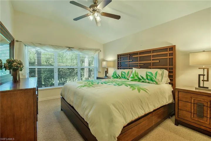 Carpeted bedroom with lofted ceiling and ceiling fan