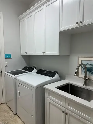 Laundry area with washing machine and dryer, cabinet space, and a sink