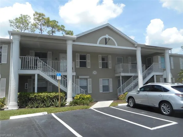 View of property featuring stairs and uncovered parking