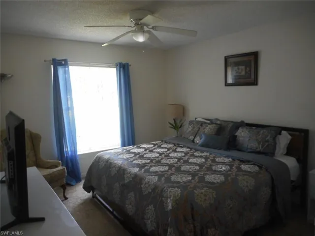 Carpeted bedroom with a textured ceiling and ceiling fan