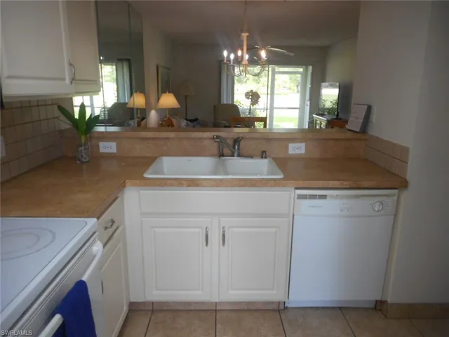 Kitchen with white cabinetry, white appliances, open floor plan, light tile patterned floors, and a peninsula