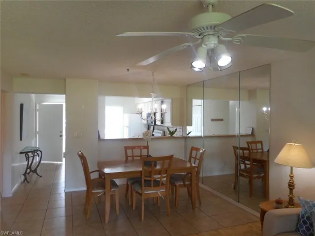 Dining space with tile patterned flooring, a chandelier, ceiling fan, and a textured ceiling