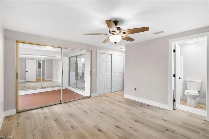 Unfurnished bedroom featuring light wood-type flooring, ceiling fan, and connected bathroom
