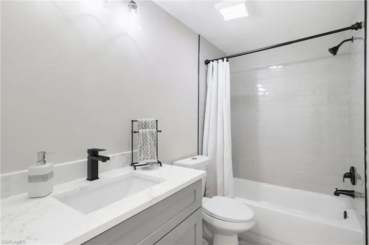 Full bathroom featuring vanity, shower / bath combo with shower curtain, and toilet