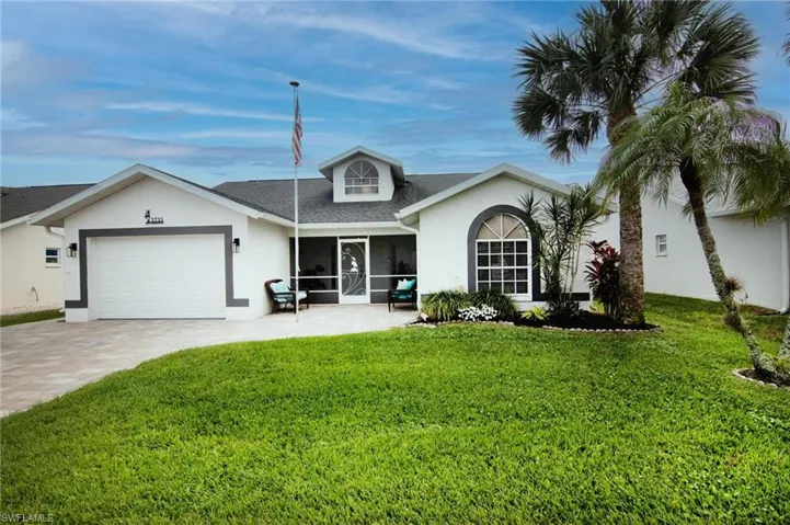 View of front facade with a front lawn, a garage, stucco siding, and decorative driveway