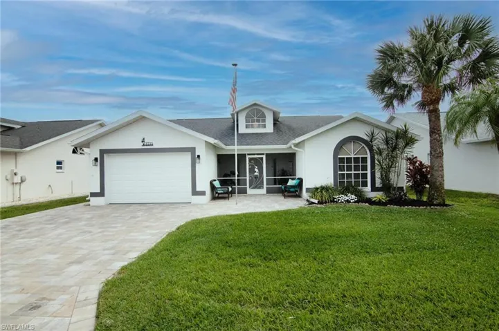 View of front of property featuring stucco siding, an attached garage, a front yard, decorative driveway, and a shingled roof