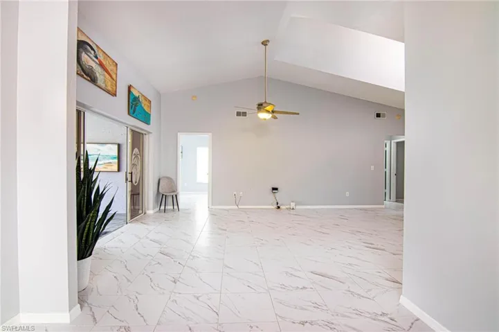Unfurnished living room with light marble finish floors, high vaulted ceiling, and a ceiling fan