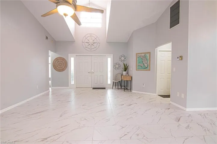 Entryway with light marble finish flooring, a ceiling fan, and a high ceiling