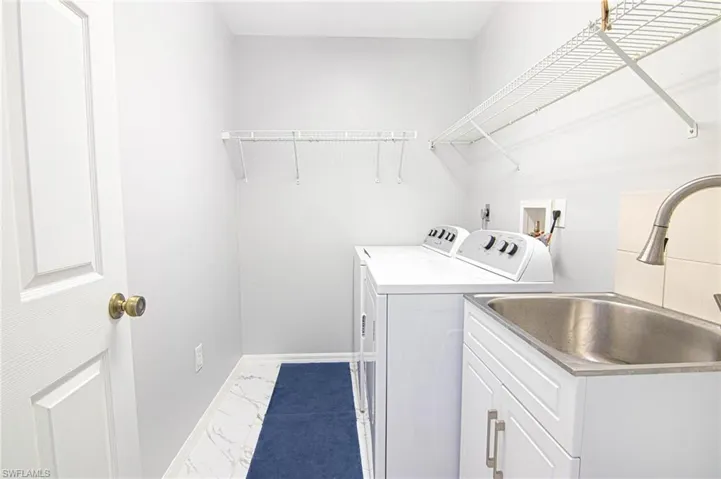 Laundry area featuring light marble finish floors and washer and dryer