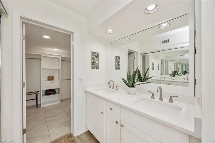 Primary Bathroom featuring recessed lighting, double vanity, light wood-style floors, and a walk in closet