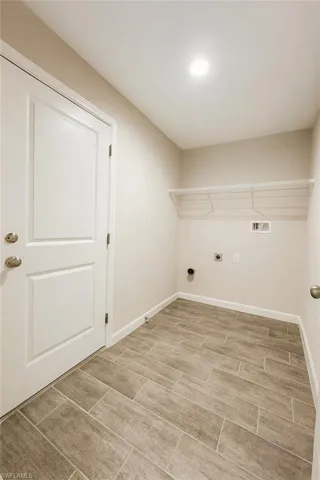 Washroom with electric dryer hookup, hookup for a washing machine, and wood tiled floors