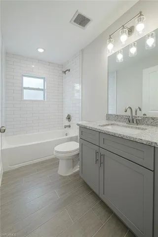 Full bath with vanity, shower / tub combination, wood finish floors, and recessed lighting