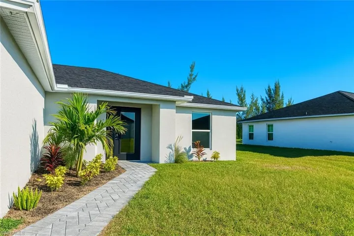 Back of property with a lawn, stucco siding, and roof with shingles