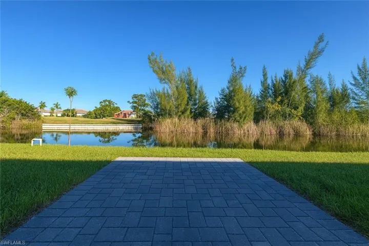 View of pool with a lawn, a water view, and a patio area