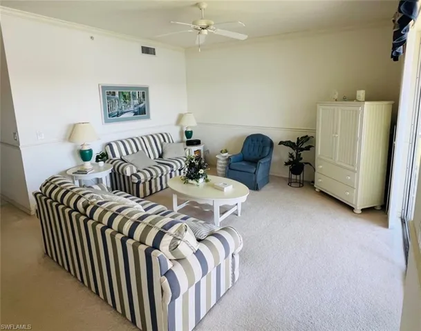 Living area featuring ornamental molding, carpet, and ceiling fan