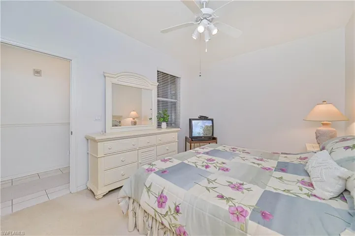 Bedroom with light carpet, a ceiling fan, and light tile patterned floors