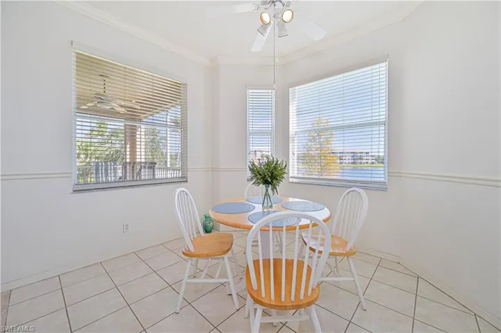 Dining room with ornamental molding, light tile patterned floors, and a ceiling fan