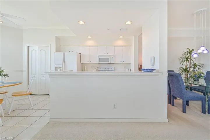 Kitchen with white appliances, white cabinetry, light colored carpet, recessed lighting, and light countertops