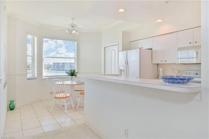 Kitchen featuring light countertops, crown molding, white appliances, light tile patterned floors, and white cabinetry