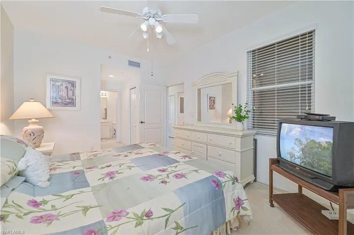 Bedroom featuring light carpet, a ceiling fan, and connected bathroom