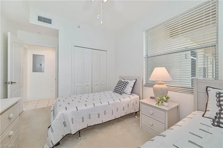 Bedroom featuring light carpet, electric panel, a closet, and a ceiling fan