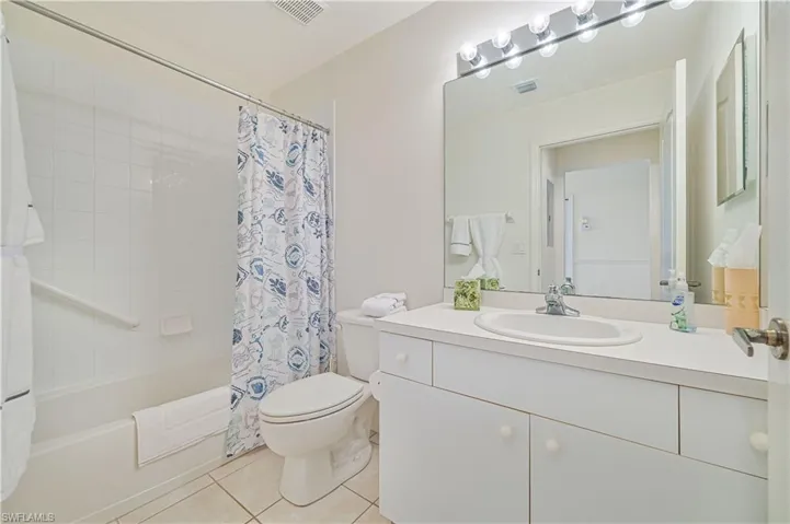 Full bathroom with vanity, light tile patterned floors, and shower / bath combination with curtain